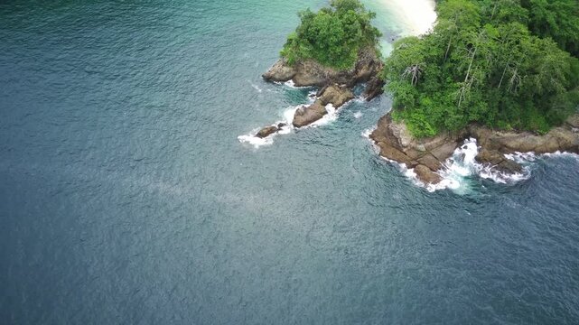 Serene beach scene with turquoise water and lush greenery in Teluk Ijo, Banyuwangi, East Java, Indonesia, featuring a small island and mountainous landscape.