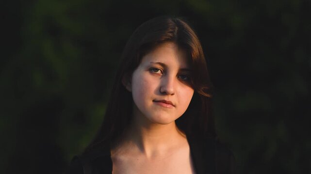 A dreamy, slow-motion portrait of a teenage girl with long hair as soft white poplar fluff floats around her. Youth, tranquility, ethereal atmosphere, summer, nature, gentle breeze, contemplation