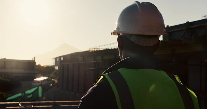 Architect, helmet or thinking with building on construction site space for safety or security. Back view, male person or contractor with hard hat for architecture, infrastructure or civil engineering