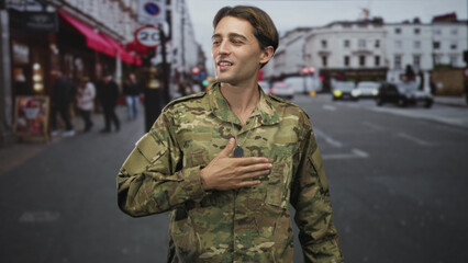 Fototapeta premium Man soldier in camouflage with hand on chest and dog tag visible on street, touching mouth mid gesture; pride service duty.