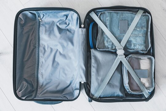 Blue suitcase interior with organized clothing compartments, mesh bags, and elastic straps