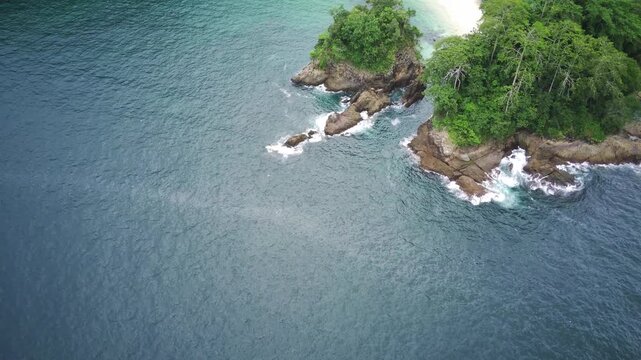 Aerial view of rugged coastline with waves crashing against rocks at Teluk Ijo, Banyuwangi, East Java, Indonesia.