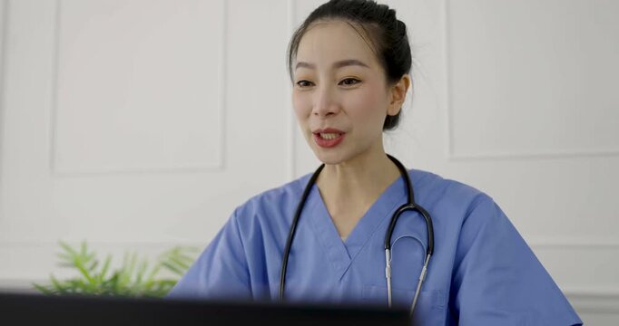 Female asian doctor using laptop for online consultation in a medical office, representing telemedicine, healthcare communication, and virtual patient clinic care.