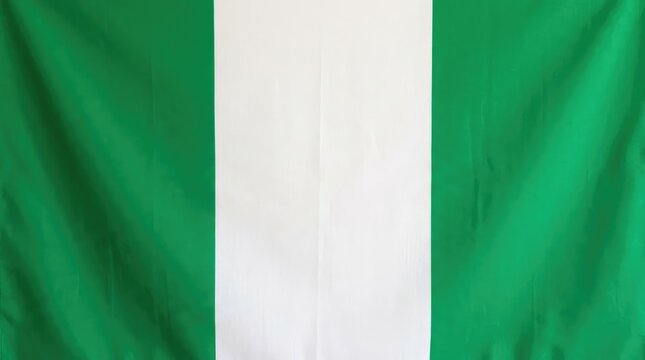 A close-up, full frame shot of the national flag of Nigeria, with its distinct vertical bands of green and white