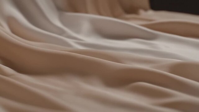 Wrinkled beige fabric texture fills the frame with smooth folds