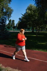 Obraz premium Curvy woman enjoys outdoor workout in vibrant park under clear blue sky