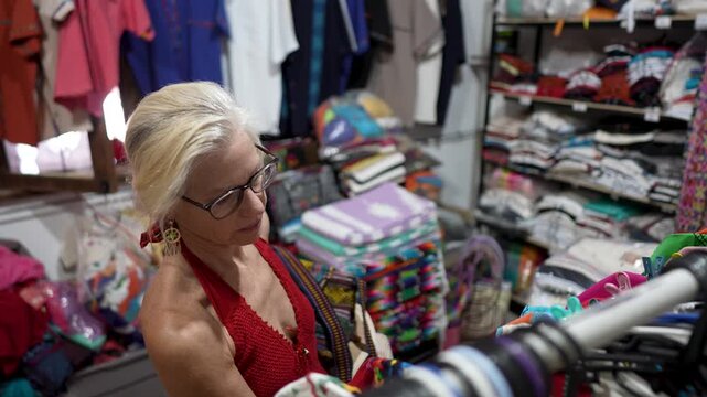 Senior woman browses through clothes in a shop in Loreto Baja California Sur Mexico while looking for the best deals and styles.