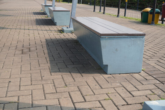 Modern concrete park benches arranged in a row on a paved walkway.