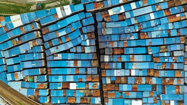 Aerial View of Dense Urban Neighborhood with Blue Rooftops Beside Railway Tracks
