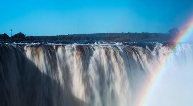 Water flows over Victoria Falls in Zimbabwe under a clear blue sky