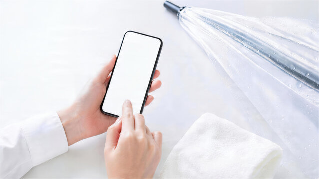 透明傘のそばで空白画面のスマートフォンを操作する手元