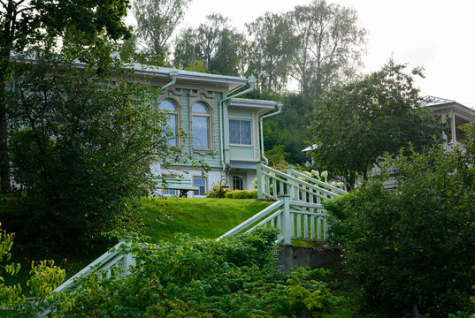 A street with dense greenery and fragments of 19th-century wooden mansions in the town of Ples, Russia