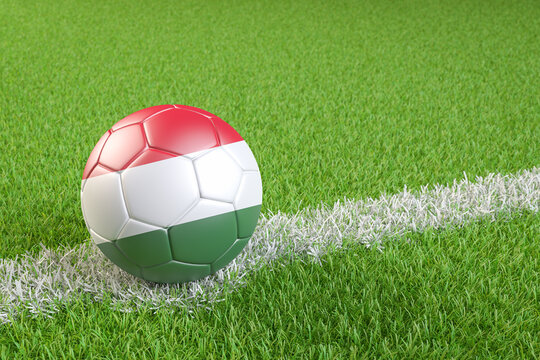 Football / soccer ball with a flag overlay of Hungary on a football pitch background. International match and national team of Hungary concept