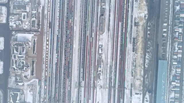 Aerial View of Snowy Freight Train Yard with Cargo Rail Tracks
