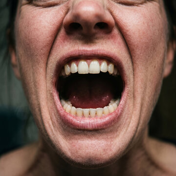 Extreme close-up of a woman screaming with eyes tightly closed, face contorted in intense pain, rage, or emotional breakdown