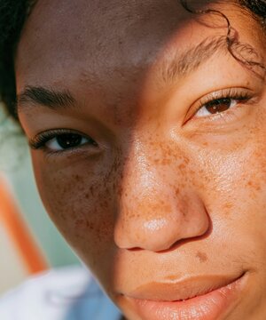 Extreme close up of a young Black womans face showing real unretouched skin texture and freckles for a skincare and honest beauty campaign