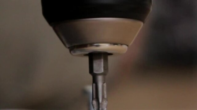 Extreme Close-Up of an Electric Screwdriver Tightening a Screw Into a Wooden Surface