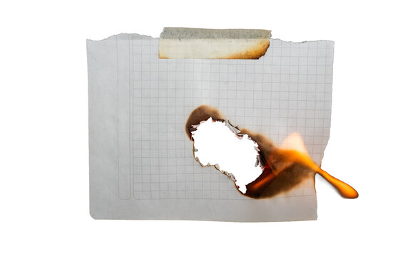 Hoja de papel cuadriculado en llamas con agujero quemado y cinta adhesiva sobre fondo negro