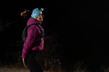 Woman Jogging at Night with Headlamp.Woman jogging at night with headlamp on, captured in dark outdoor environment. © .shock