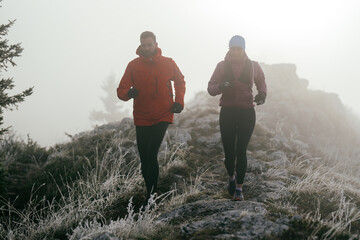 Obraz premium Trail running couple man and woman running on a mountain path