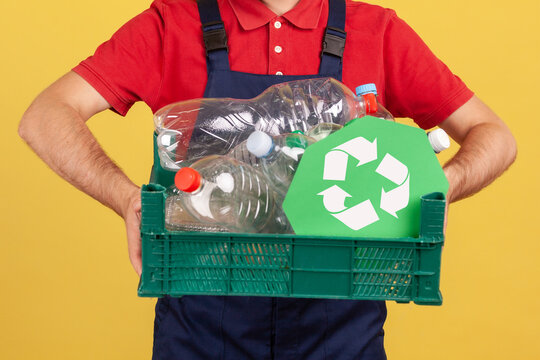 Anonymous worker holding box with plastic bottles for recycling to promote environmental protection or waste sorting isolated over yellow background with copy space