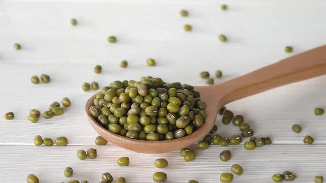 Wooden spoon filled with small green mung beans