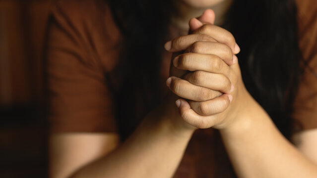 Woman holding hands together in prayer and meditation, front view, Christian worship, spiritual reflection, mindfulness, and seeking blessings in times of difficulty.