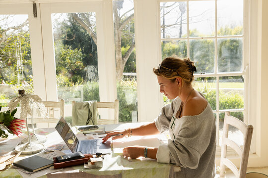 young woman artist in her studio using laptop and working on a pencil drawing