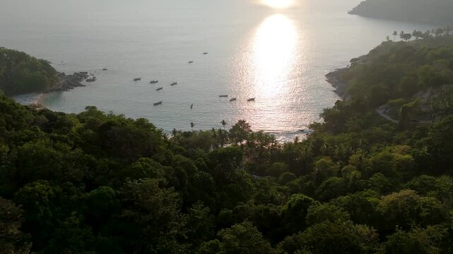 Golden sunset light illuminates the tropical jungle landscape and Andaman Sea coastline in Phuket, Thailand