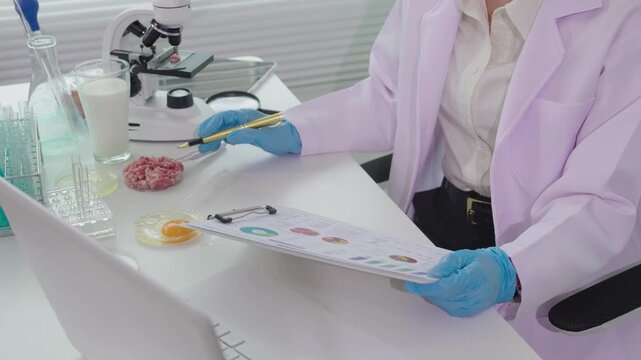 Food scientist using pipette to drop chemical on raw egg yolk in petri dish, conducting food safety and quality control testing in laboratory.