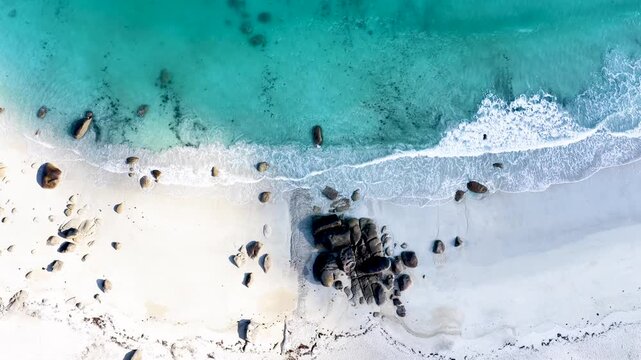 Faszinierende Drohnenaufnahme vom Plage de Boutrouilles: T&uuml;rkisblaues Wasser und wei&szlig;er Gischt-Schaum treffen auf hellen Sandstrand und markante, dunkle Granitfelsen.