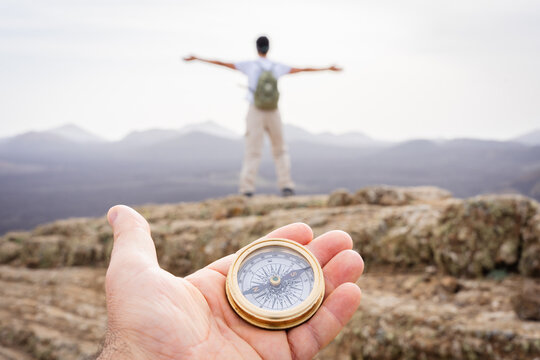 Man's hand holding a compass, guiding a hiker finding freedom and direction on a mountain top adventure