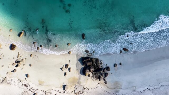 Faszinierende Drohnenaufnahme vom Plage de Boutrouilles: T&uuml;rkisblaues Wasser und wei&szlig;er Gischt-Schaum treffen auf hellen Sandstrand und markante, dunkle Granitfelsen.