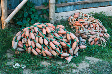 Fishing Net Floats and Rope Bundles on Grass Near Coastal Shed © CreativeAi
