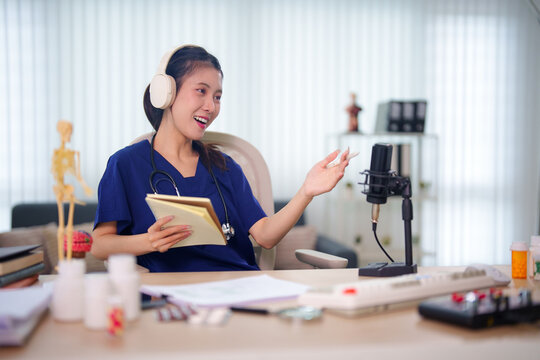 Young Asian female healthcare professional recording medical podcast with microphone wearing scrubs and headphones while explaining content in bright modern