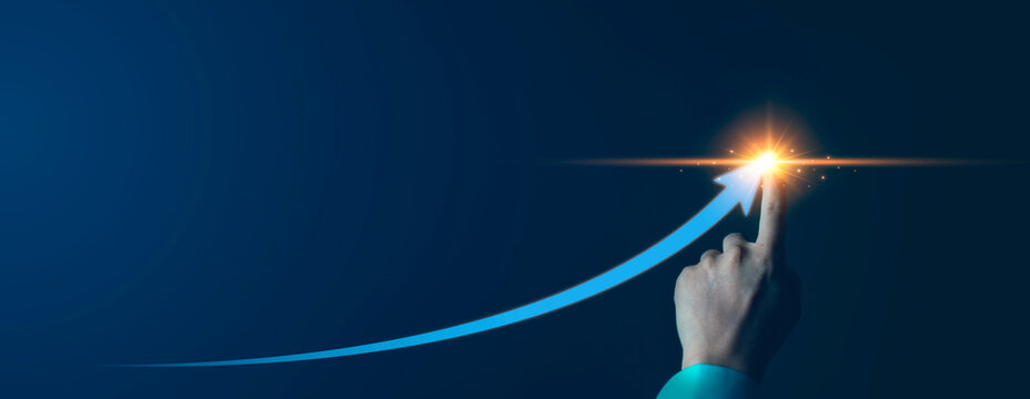 Hand reaching to success, achievement, trend future and profit goal on dark background. Strategic planning future. Businessman pointing at glowing blue arrow pointing upwards business growth concept