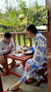 Tourists eating traditional local food on villa balcony with tropical palm trees view in Sri Lanka