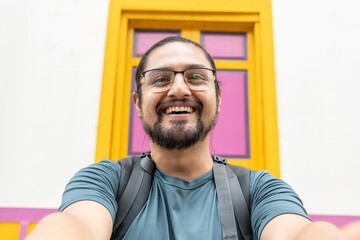 Obraz premium Laughing man with backpack taking pov selfie outdoors