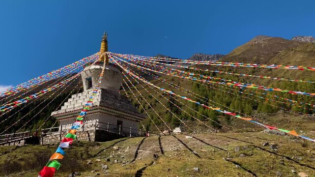 Buddhist stupa with colorful prayer flags on Himalayan mountain hillside in Himalayas