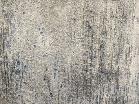 An old weathered concrete wall with a rough and porous texture. A large portion of the surface is covered in dark mold stains and patches of moss.