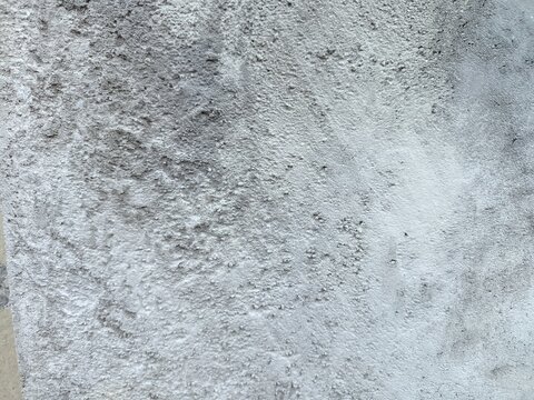 An old weathered concrete wall with a rough and porous texture. A large portion of the surface is covered in dark mold stains and patches of moss.