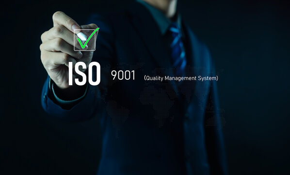Businessman touching virtual checkmark icon for ISO 9001 certification on digital world map background, symbolizing quality management, compliance, global standards, and corporate assurance in modern.