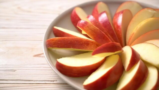 Sliced red apple on a white plate with a light background