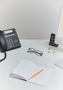 Modern office desk with telephone, notebook, and computer setup