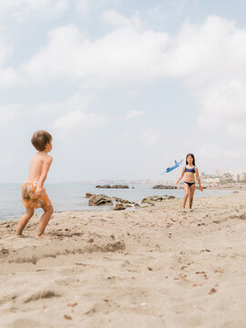 Brother and sister playing together with plane at beach 