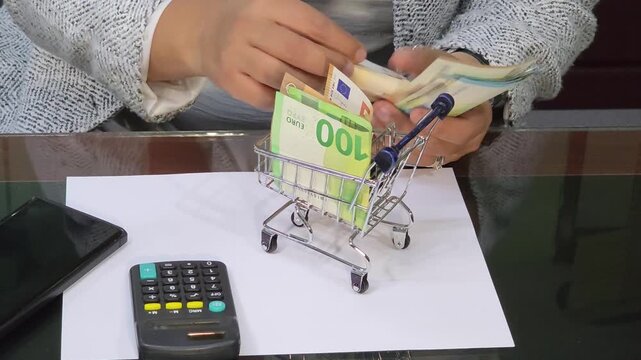 hands folding euro banknotes and putting them inside a shopping cart