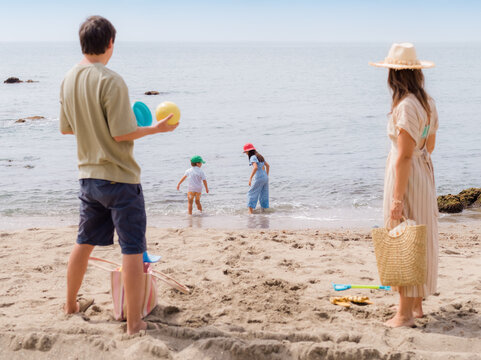 Parents unpacking while kids trying water at beach 