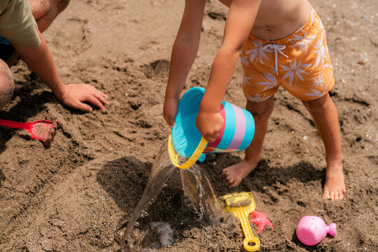 Father and son are building sand castle together 