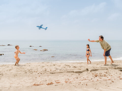 Father playing with little kids at beach 