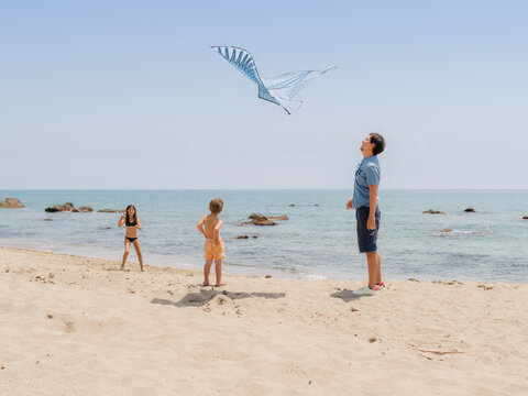 Father launching kite with kids 